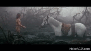 film screenshot of boy trying to pull a horse out of the mud